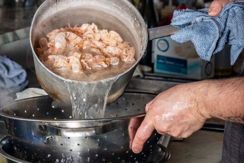 pouring hot water down a kitchen sink to clear grease clog
