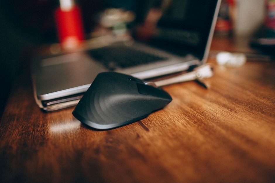 Wireless mouse beside laptop on wooden desk