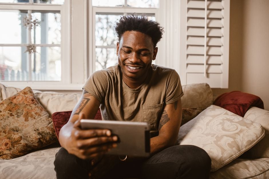 A happy person using a tablet comfortably at home
